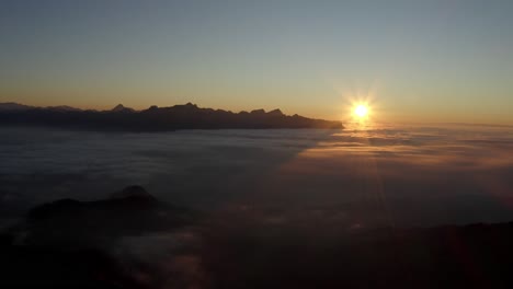 High-flight-above-fog-at-sunset,-the-Alps-in-the-background---Switzerland