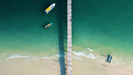 Aerial-of-white-sand-beach-with-wooden-pier-on-4k-Beach,-Koh-Rong,-Cambodia