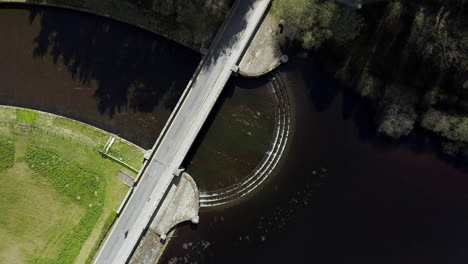 Static-Aerial-Shot-of-Cyclist-Crossing-Dam-in-Yorkshire,-England