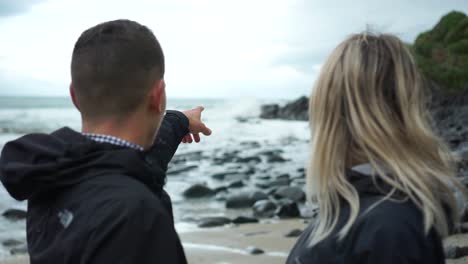SLOWMO---Young-attractive-couple-from-behind-looking-at-ocean-in-New-Zealand