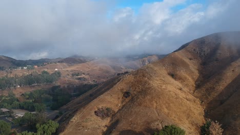Drone-footage-of-helicopter-flying-over-cloudy-mountains-in-Los-Angeles,-California