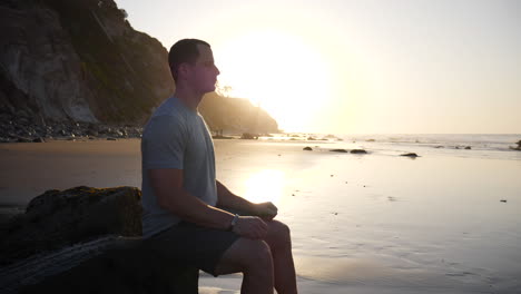 Ein-Starker-Junger-Mann-In-Silhouette-Sitzt-In-Einer-Meditationspose,-Um-Stress-Abzubauen-Und-Achtsamkeit-Und-Positivität-Bei-Sonnenaufgang-In-Santa-Barbara,-Kalifornien,-Zeitlupe-Zu-Trainieren
