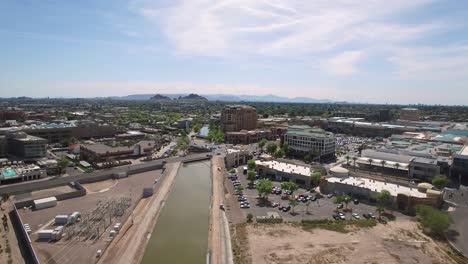Aerial-slow-push-up-Arizona-Canal-Trail-to-the-center-of-old-town-Scottsdale,-Camelback-and-Scottsdale-Road