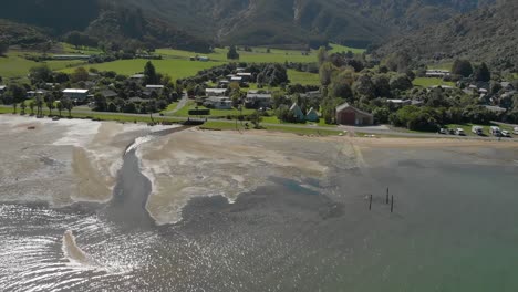 Flug-über-Meerwasser-Mit-Der-Stadt-Anakiwa-Im-Hintergrund,-Queen-Charlotte-Sound,-Marlborough-Sounds,-Südinsel,-Neuseeland---Luftaufnahme