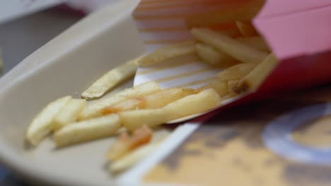 Close-up-of-fries-in-a-container-on-a-tray-blowing-in-the-wind-ready-to-eat-as-a-meal-for-lunch