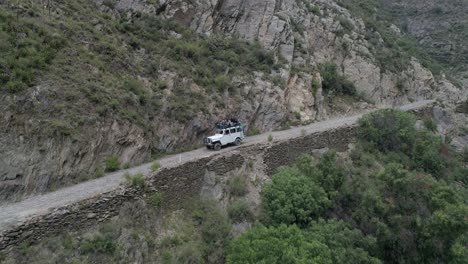 Aerial-drone-shot-of-a-Willis-Jeep-with-tourist-in-a-narrow-road-in-Real-de-Catorce,-San-Luis-Potosi,-Mexico