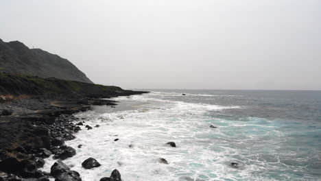 Luftaufnahmen-Von-Wunderschönen-Meereswellen,-Die-An-Der-Küste-Hawaiis-Zusammenbrechen,-Mit-Bergen-Im-Hintergrund