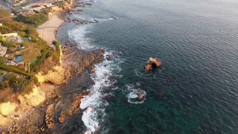 Flying-over-million-dollar-beach-front-luxury-homes-and-a-private-beach-in-beautiful-Laguna-Beach-California-tide-pools-at-Sunset-in-stunning-4k-resolution