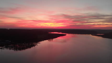 Rotating-drone-footage-of-a-stunning-sunset-with-a-lake-and-forests-on-each-side