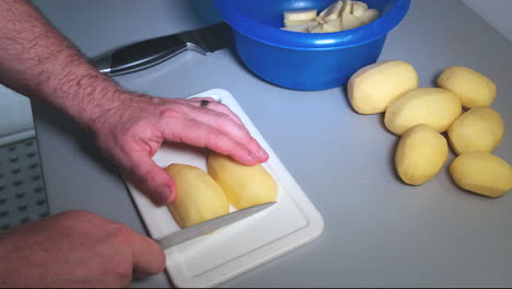Die-Hände-Eines-Mannes-Halten-Ein-Messer-Und-Schneiden-Kartoffeln-In-Scheiben,-Ein-Mann-Bei-Der-Hausarbeit