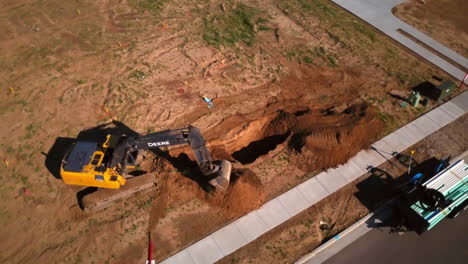 A-drone-shot-of-a-construction-worker-digging-a-hole-in-the-morning-for-the-starting-of-a-new-house-in-the-suburbs
