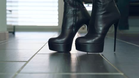 Girl-struts-in-front-of-the-camera-in-black-faux-leather-high-heels-block-heel-boots-around