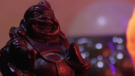Buddha-Miniaturstatue,-Lachend,-Nahaufnahme,-Makro-Mit-Wechselnden-Farben-Im-Hintergrund