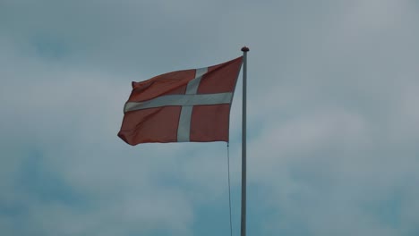 Danish-national-flag-flutters-in-the-wind-with-blue-sky-in-background-in-slightly-slow-motion