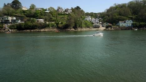 Gazing-across-the-Fowey-estuary,-river-at-Bodinnick-with-a-fast-motor-boat-crossing-the-scene-on-a-hot-spring-day