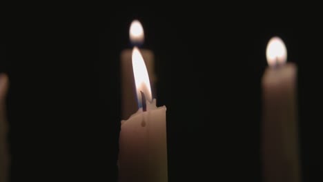 Four-white-candles-lit-and-a-fast-pan-across-them-in-slow-motion