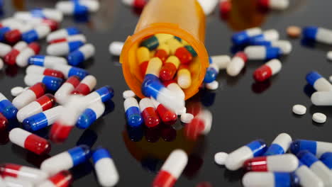 Many-prescription-pills,-drugs-and-antibiotics-falling-in-slow-motion-on-an-orange-pharmacy-medicine-bottle