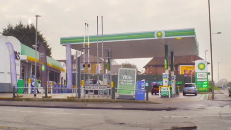 Gas-filling-station-and-convenience-store-with-female-customer-running-to-her-car