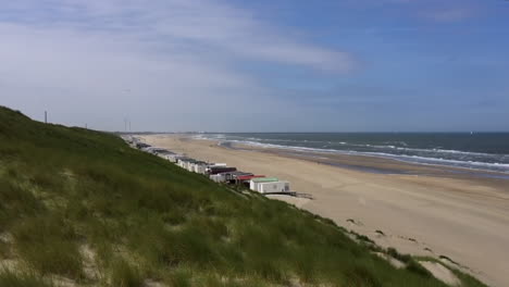 A-net-row-of-white-beachside-cabins-on-a-white-sandy-beach-in-Wijk-an-Zee,-Netherlands