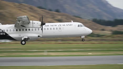 Slowmo---Verkehrsflugzeug-Landet-Am-Flughafen-Queenstown,-Neuseeland-Mit-Bergen-Im-Hintergrund