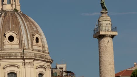 Tilt-close-shot-of-Church-of-Saint-Mary-of-Loreto's-dome-and-the-Trajan's-column-on-the-top-saint-Peatro-statue