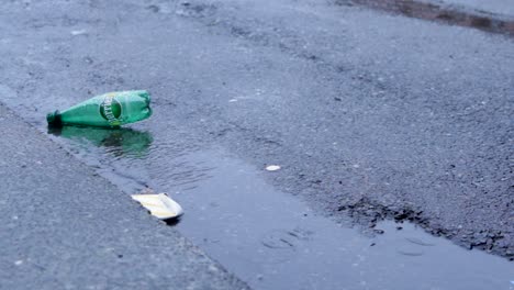 a-perrier-bottle-and-cup-litter-a-rainy-gutter
