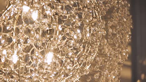 Close-up-of-glass-crystal-beads-dropping-from-a-chandelier-indoors---Macro,-bokeh-effect,-shallow-depth-of-field