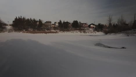 Panning-shot-of-a-frozen-pond-amidst-a-suburban-neighbourhood