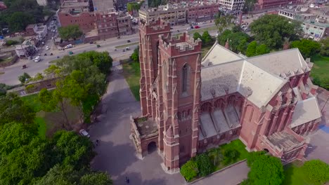 Top-Aerial-view-of-a-beautiful-Church-building,-Traffic-is-moving-on-the-other-side-road-of-the-Church,-Beautiful-greenery-around-the-Church