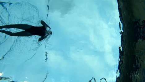 Slow-Motion-Underwater-shot-of-a-woman-swimming-through-the-lane-in-a-swimming-pool-using-the-Breast-Stroke