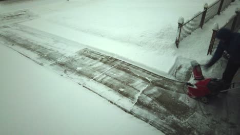 A-man-clearing-his-snow-in-his-driveway-with-a-snow-blower-done-in-time-lapse-as-he-clears-it-very-fast