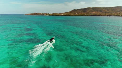 Epic-aerial-of-a-speed-boat-making-waves-in-the-Caribbean-island-of-Carriacou,-Grenada
