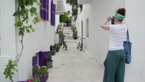 A-women-taking-pictures-of-a-purple-windowed-narrow-street