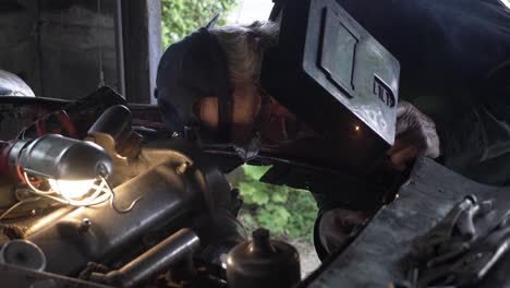 LOCKED-OFF-view-of-car-mechanic-welding-on-front-of-car