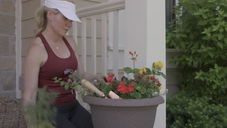 Eine-Frau-Arrangiert-Blumen-Und-Pflanzen-In-Ihrem-Blumentopf-Auf-Der-Veranda