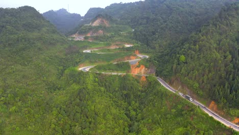 Aerial-shot-of-a-winding-road-full-of-switchbacks-cutting-through-the-misty-mountains-of-Vietnam