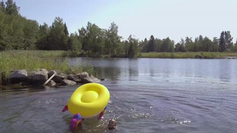 Summer-break-kids-having-fun-in-the-water,-boy-riding-and-falling-off-inflatable-unicorn