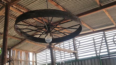 Unique-rusted-old-iron-wheel-used-as-light-fixture-in-barn