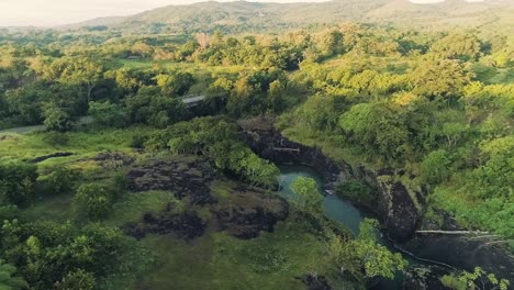 Drone-footage-of-a-single-road,-a-small-bridge-and-a-river-during-a-sunrise