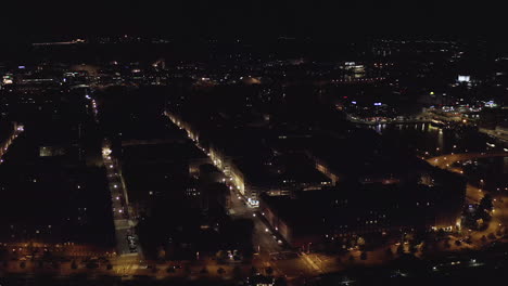 Aerial,-tracking,-drone-shot,-panning-over-buildings-and-streets,-in-the-Kruununhaka-cityscape,-revealing-the-Helsinki-cathedral,-in-the-downtown,-full-of-lights,-on-a-clear-night,-in-Uusimaa,-Finland