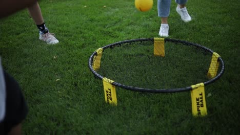 Eine-Gruppe-Kinder-Spielt-Spikeball,-Indem-Sie-Den-Kleinen-Gelben-Ball-Ins-Netz-Schlägt
