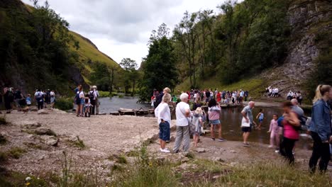 Timelapse-of-Dovedale-Stepping-Stones-in-Derbyshire,-Peak-District,-England,-UK-showing-crowds-of-tourists-crossing-the-stepping-stones-over-the-river-Dove