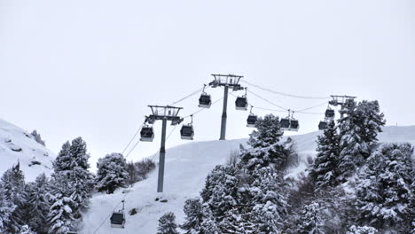 Time-lapse-of-a-ski-lift-bubble-going-over-a-tree-covered-mountain-covered-in-snow