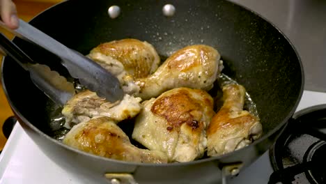 Pan-fried-chicken-drumsticks-and-thighs-in-hot-oil,-use-tongs-to-check-browned-crispy-skin