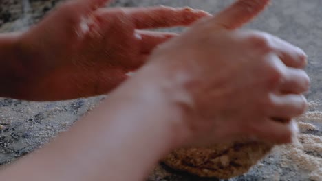 Woman-hands-kneading-whole-wheat-dough-on-floured-countertop
