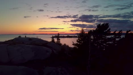 Fly-Past-Inukshuk-on-Rocky-Pine-Tree-Island-just-after-Sunset,-Drone-Aerial-Wide-Dolly-In