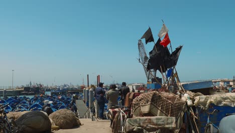 Gente-Marroquí-Mirando-El-Puerto-Con-Barcos-Azules-En-Essaouira