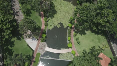 aerial-view-of-modern-urban-park-featuring-lakes,-lush-gardens,-bridges,-green-space,-pathways-and-trees