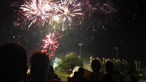 A-fireworks-finale-with-people-watching-on-the-banks-of-the-Arkansas-River-in-Wichita,-Kansas