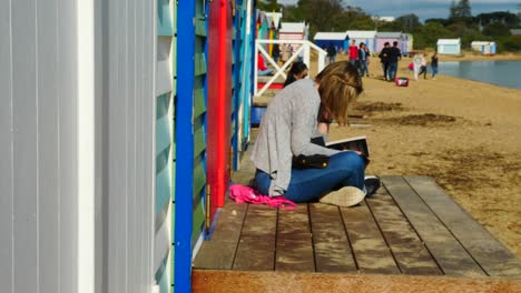Girl-reading-Book-at-Brighton-Bathing-Boxes,-Melbourne,-Australia